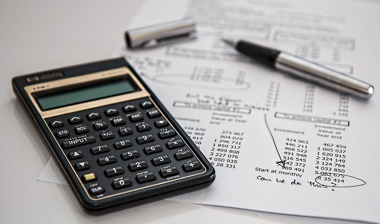 Financial analysis with calculator, investment documents, and pen representing fractional CFO services for business cash flow management, financial strategy, and profitability optimization.