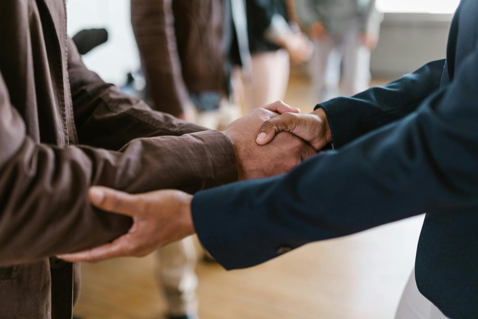 Business leaders shaking hands to establish trusted partnerships and strategic collaboration through advisory board services for organizational growth.